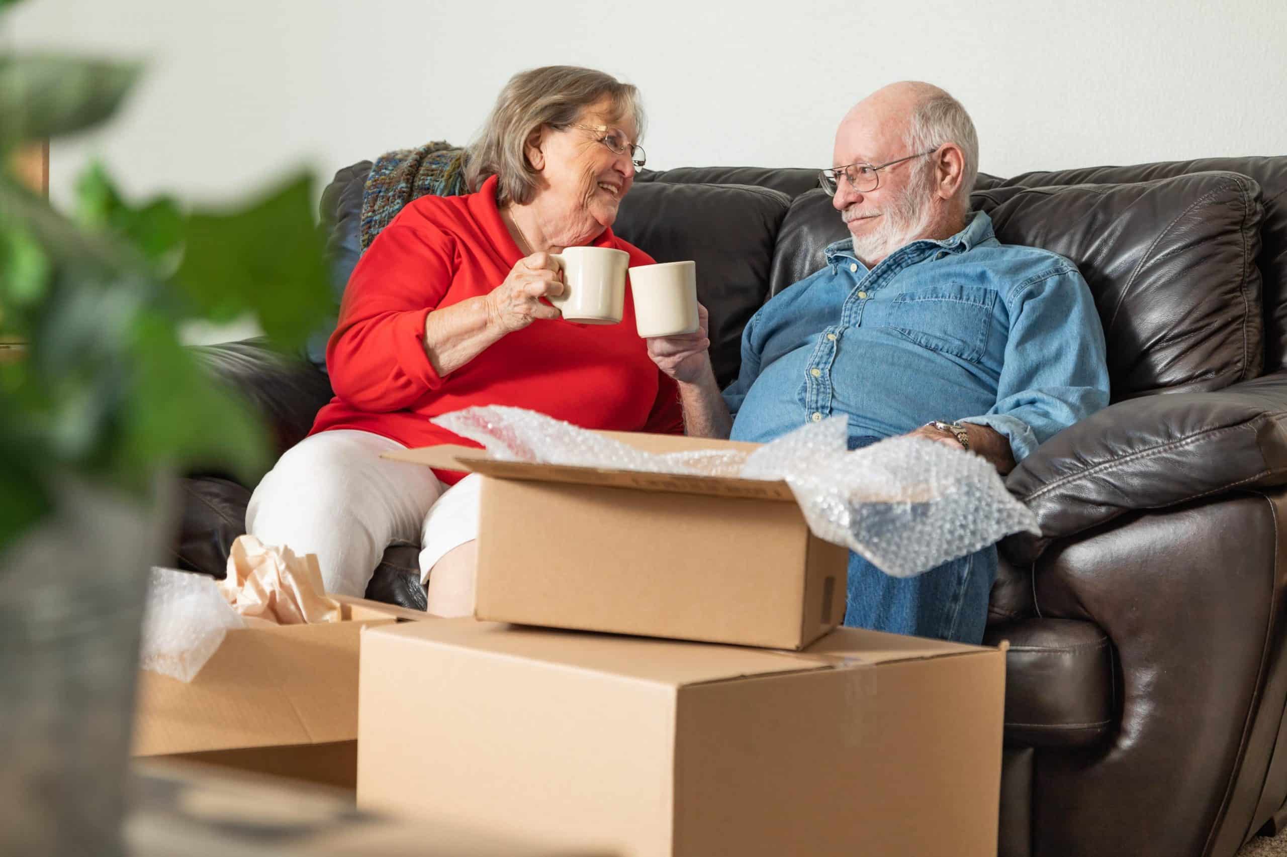 Senior woman and man enjoying coffee surrounded by moving boxes
