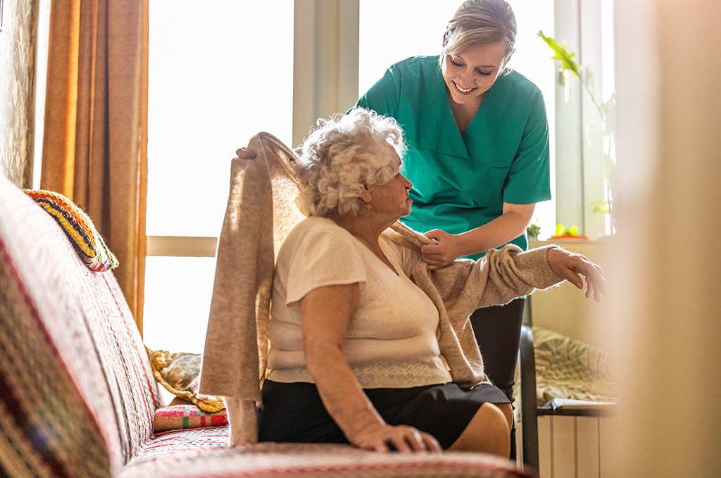 Caregiver or LNA helping senior woman get dressed