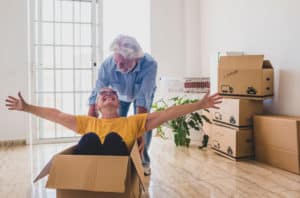 senior man and woman playfully packing cardboard moving boxes